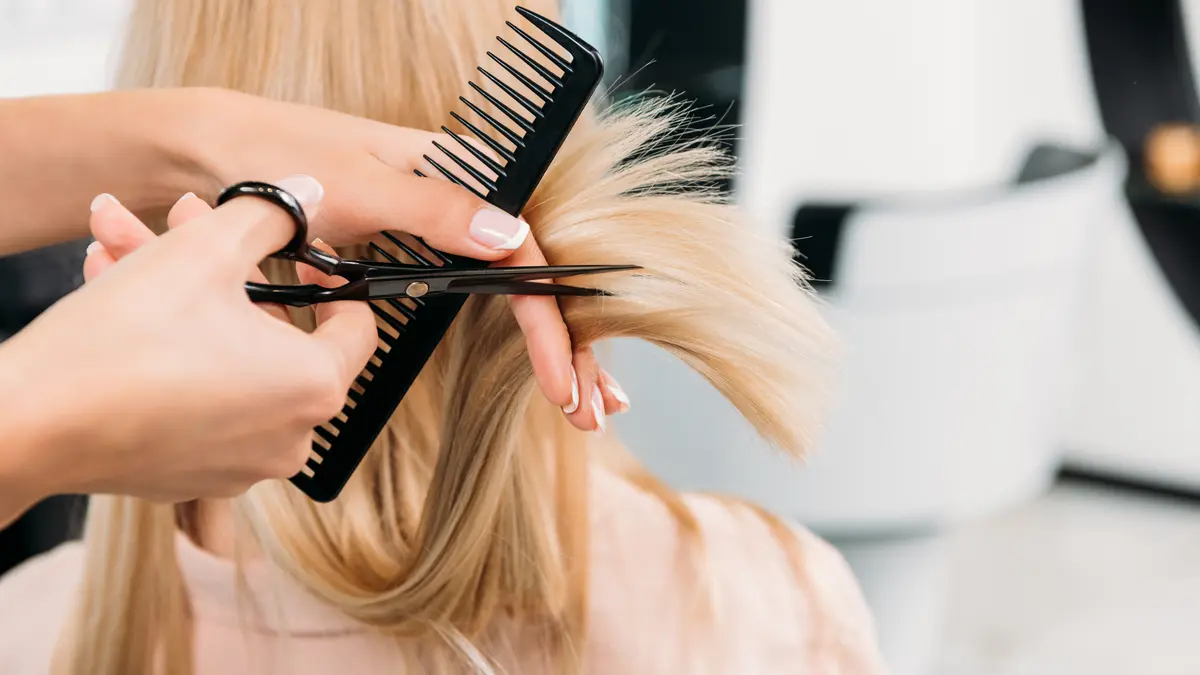 Person bekommt Haare beim Friseur geschnitten
