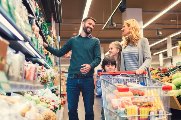 junge Familie mit Kind mit Einkaufswagen im Supermarkt