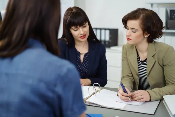 Zwei Frauen sitzen bei einer Beratung zu Versicherungen