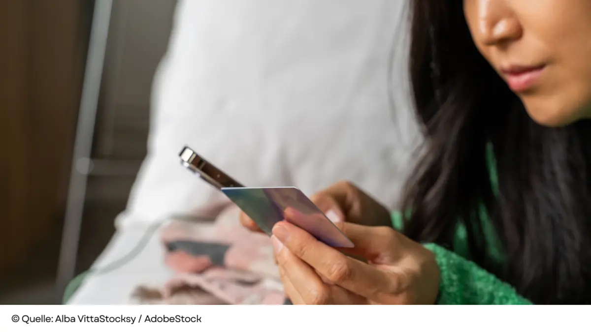 Nahaufnahme einer Frau, die beim Online-Shopping eine schimmernde Zahlungskarte und ein Smartphone benutzt.