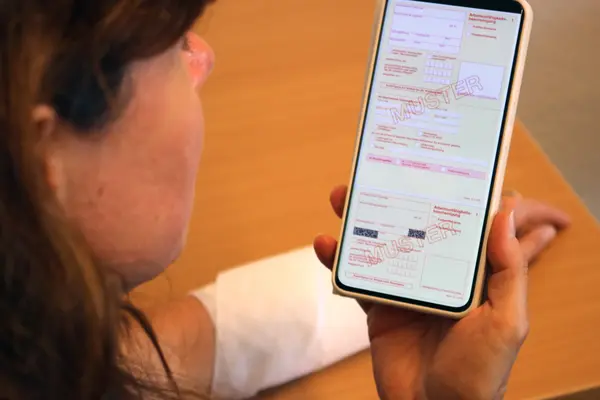 Frau hält Smartphone mit Arbeitsunfähigkeitsschein in der Hand