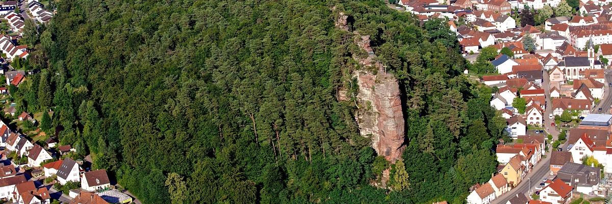 Ein Wald mit einem Felsen und drumherum eine Kleinstadt.
