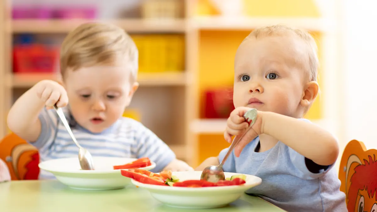 zwei Kleinkinder am Tisch mit Essen