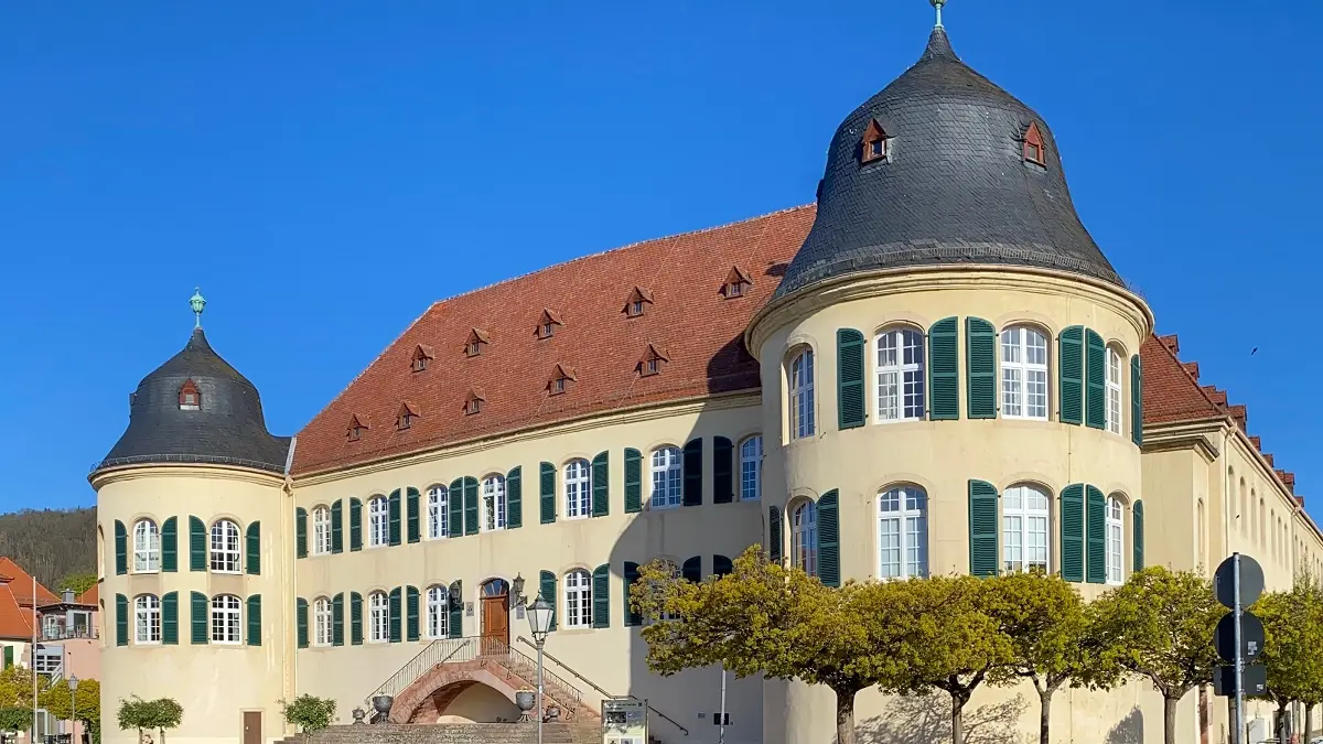 Ein altes Gebäude mit rechts und links jeweils einem breiten Turm. Im Hintergrund ist ein blauer Himmel zu sehen.