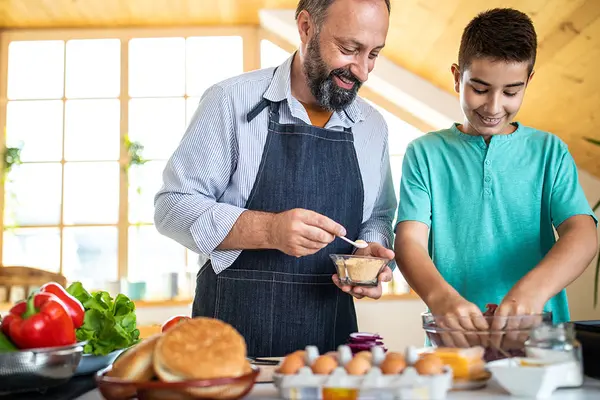 Ein älterer Mann und ein Junge stehen in einer Küche und bereiten Essen zu