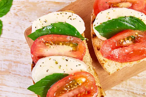 Bruschetta mit Tomate, Mozzarella und Basilikum auf einem Brettchen
