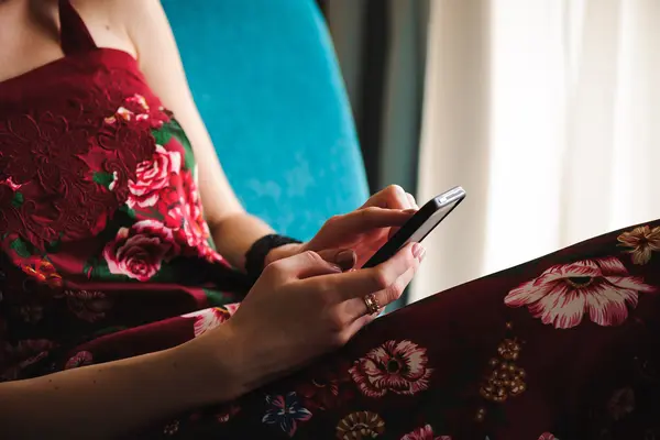 Eine Frau im Kleid tippt auf ihrem Smartphone.