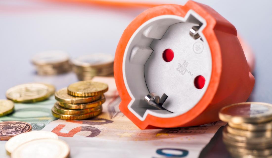 Steckdosen liegen auf Geldscheinen und Geldmünzen