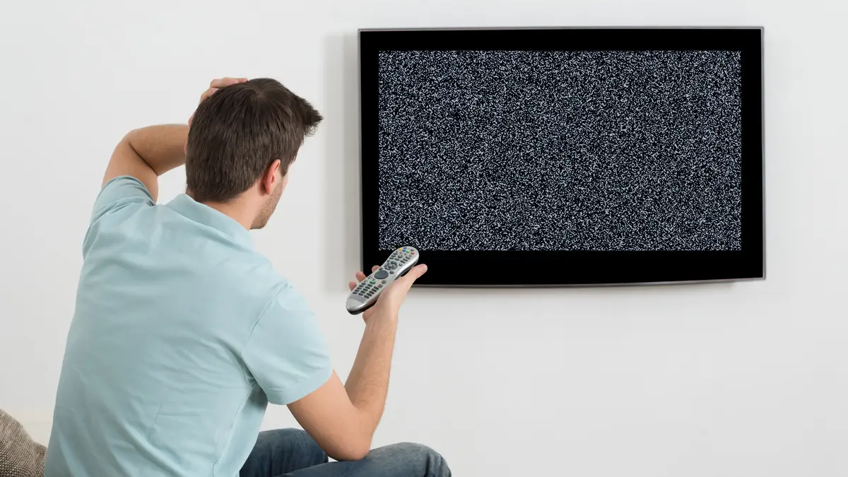 Mann sitzt vor defektem Fernsehgerät