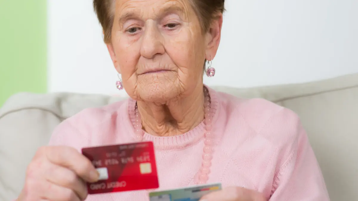 Seniorin schaut sich ihre Krankenkasse Versichertenkarte an