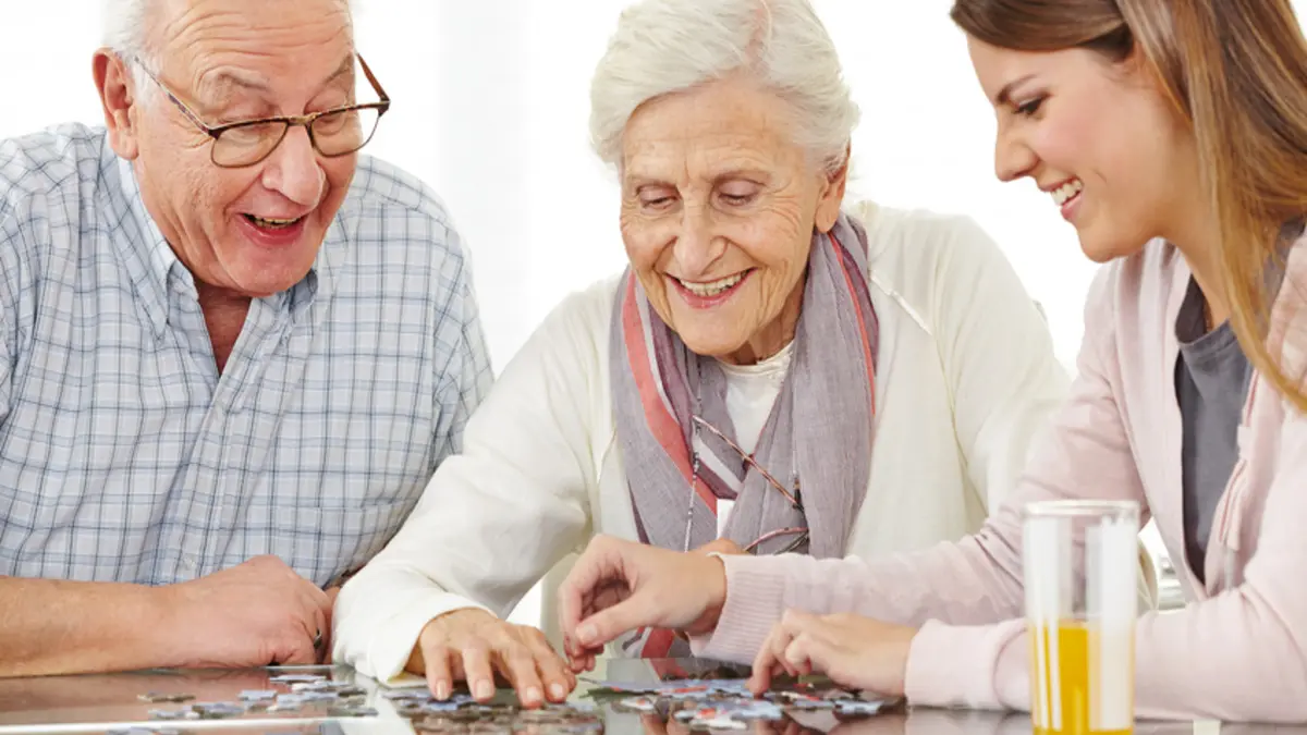 älteres Paar und junge Frau puzzeln