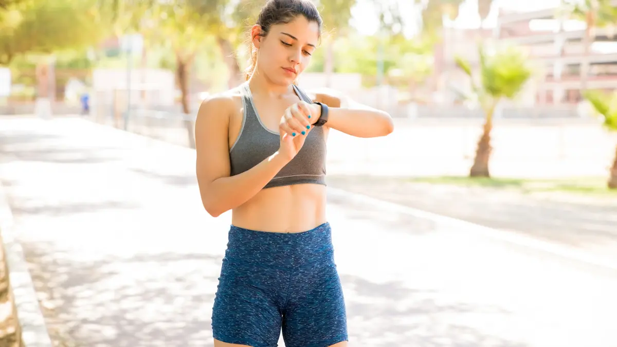 Joggerin prüft auf einer Smartwatch ihre Gesundheitsdaten
