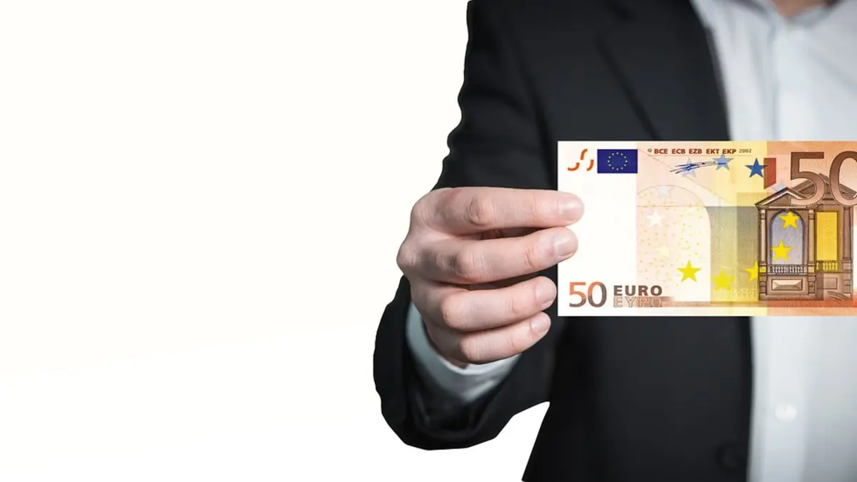 Eine Person hält einen 50-Euro-Schein in den Händen.