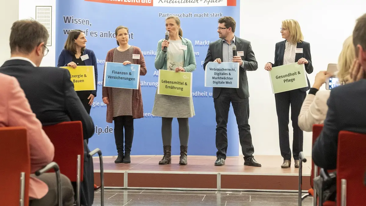 Personen halten Schilder auf der Bühne hoch.