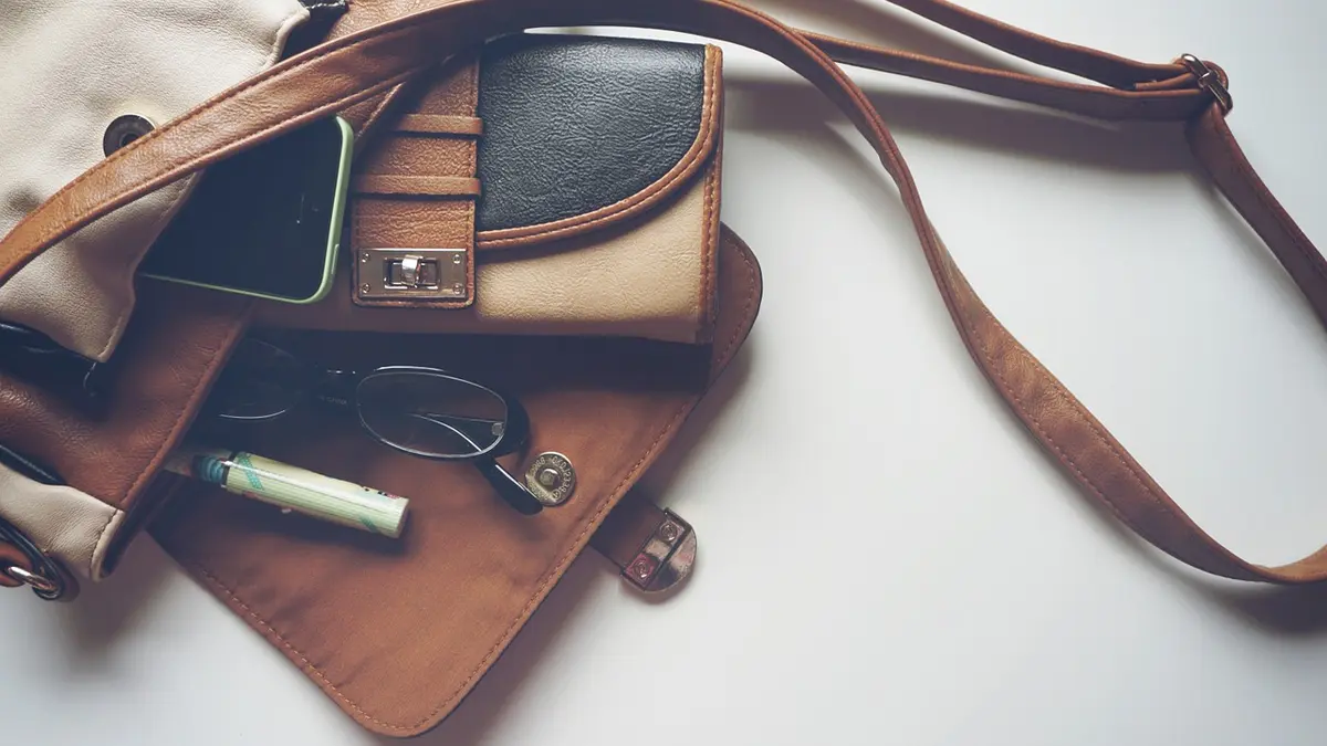 geöffnete Handtasche mit Portemonnaie, Stift und Brille
