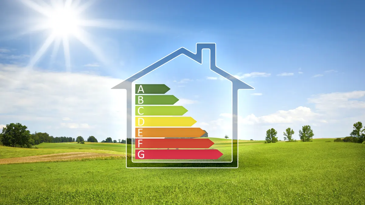 Haus mit Effizienzs-Skala vor grüner Landschaft mit Sonnenschein