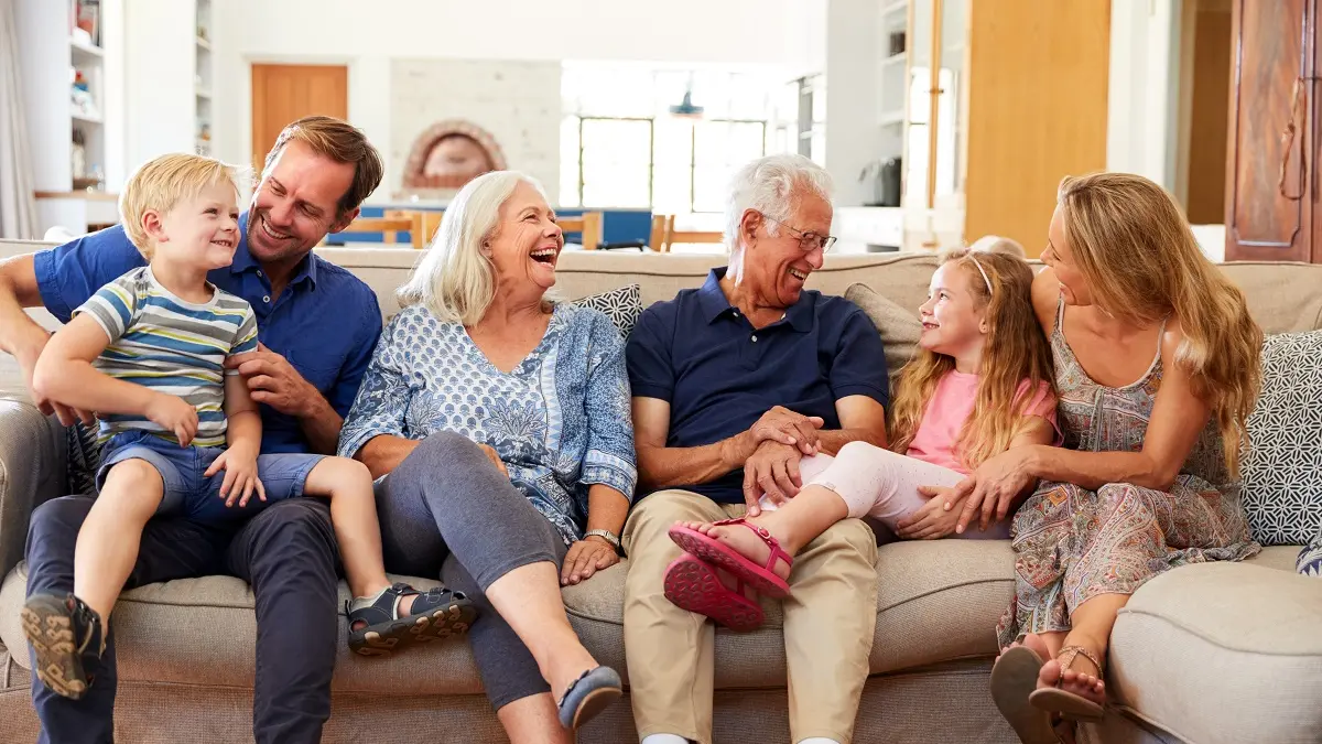 Eine Familie mit Kindern und Großeltern sitzt auf dem Sofa