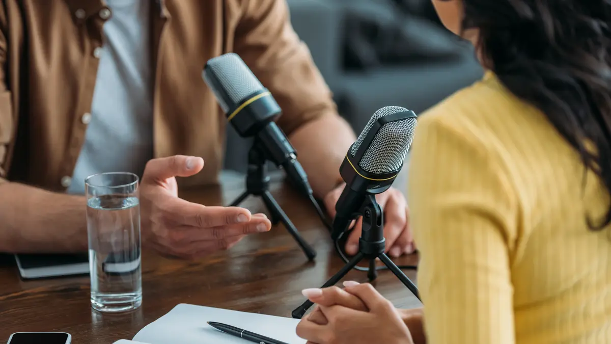 Mann und Frau gegenüber bei der Aufnahme eines Podcasts