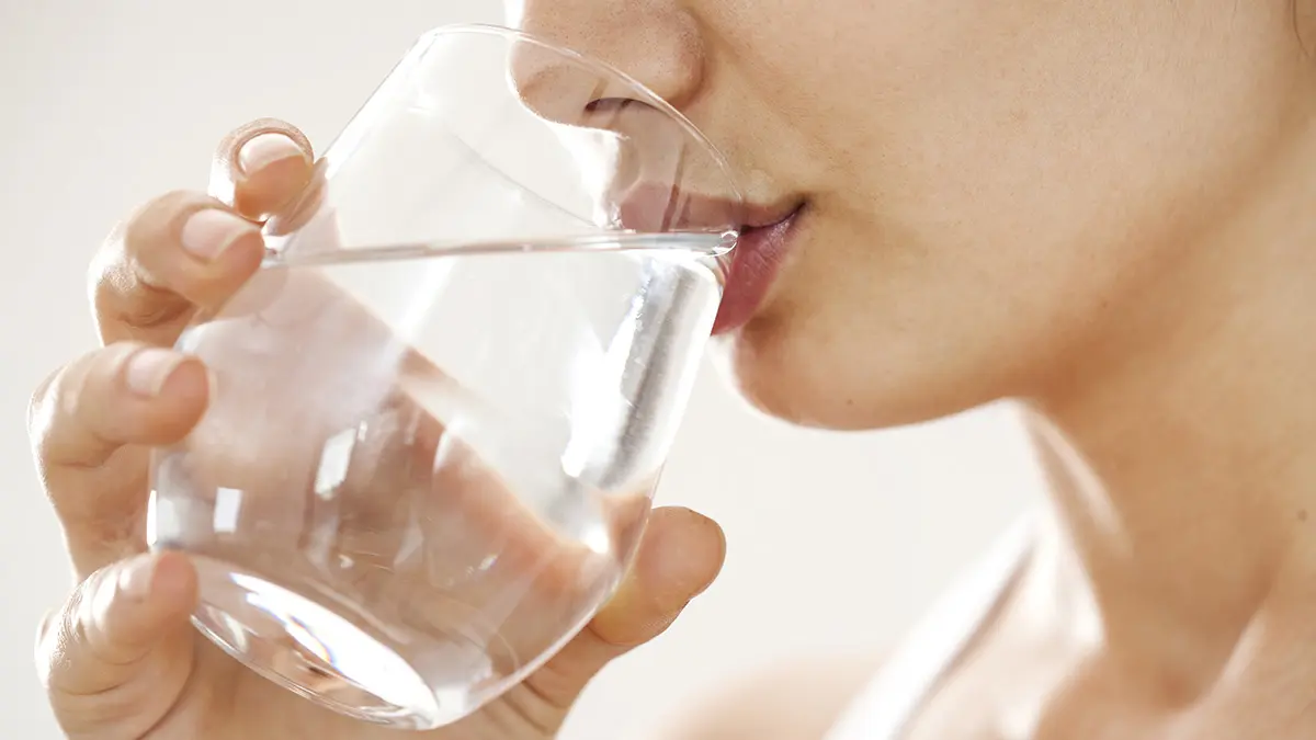 Frau trinkt Wasser aus einem Glas