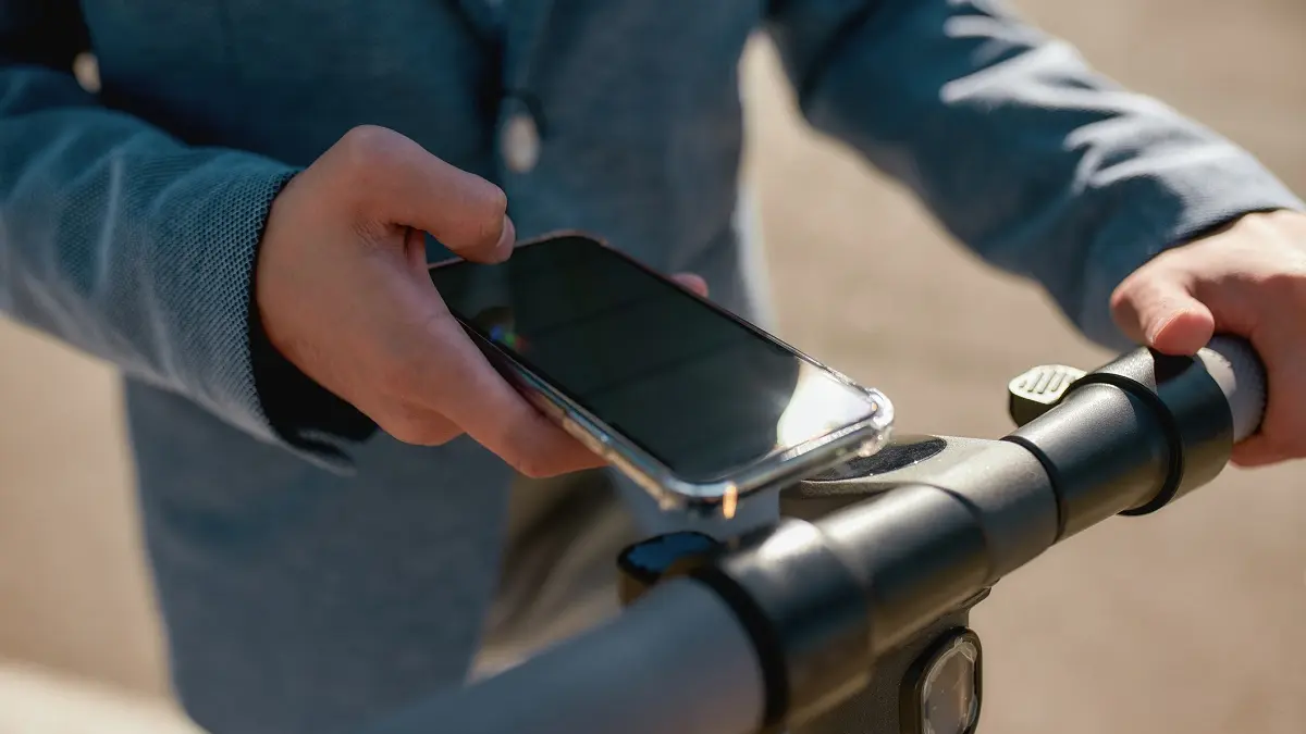 Eine Person hält sein Smartphone an einen E-Roller.