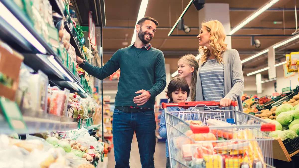 junge Familie mit Kind mit Einkaufswagen im Supermarkt