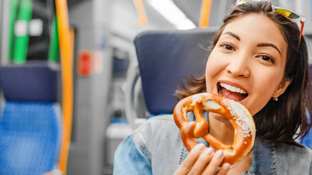 Frau isst eine Bretzel im Zug.