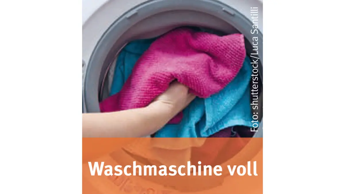 Jemand stopft Wäsche in eine Waschmaschine