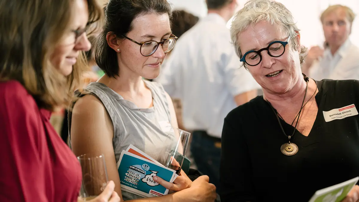 Zwei Frauen lassen sich von einer dritten Frau etwas erklären.