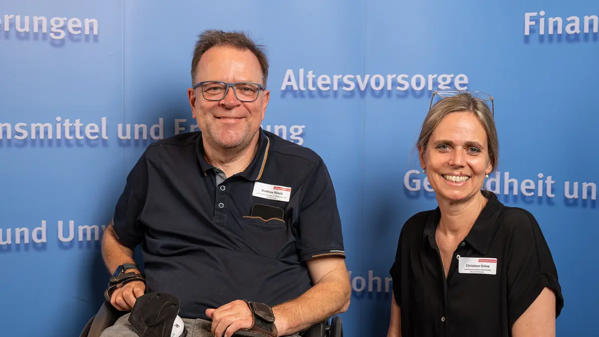 Ein Mann und eine Frau stehen vor einer Fotowand.