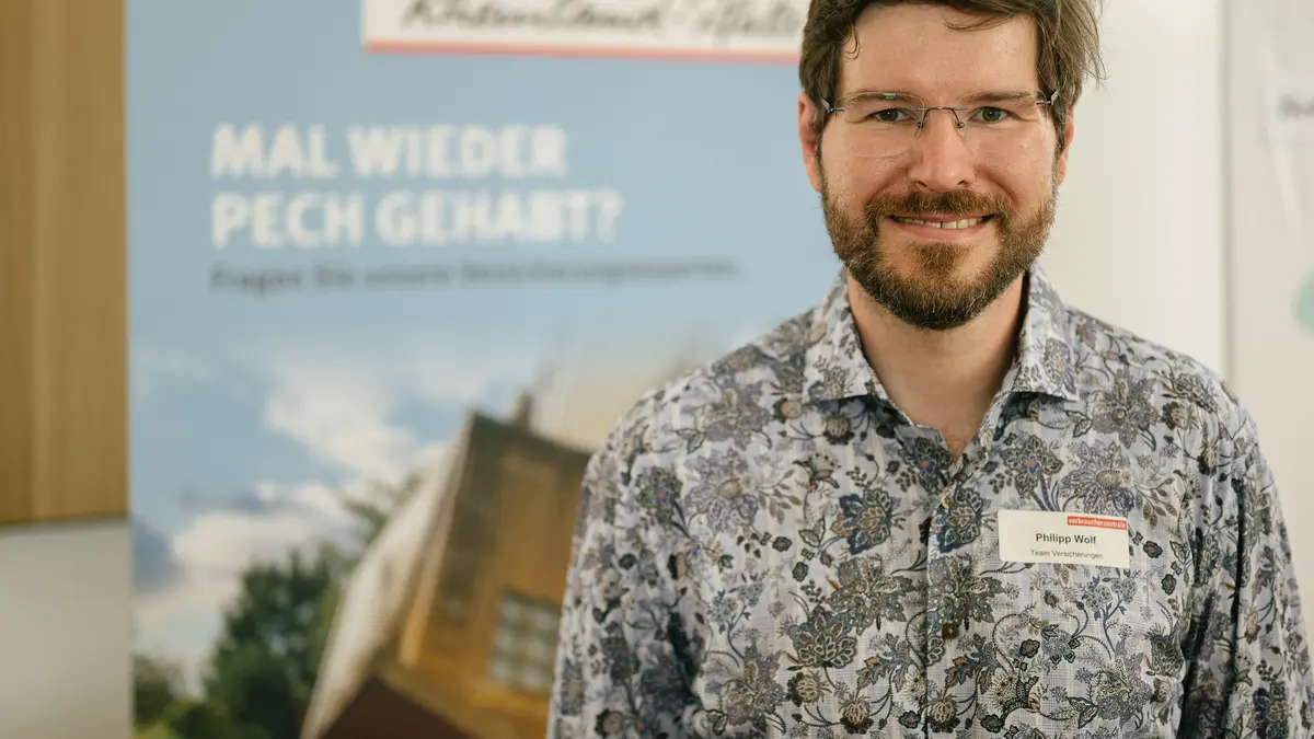 Ein Mann vor einem Roll-up. Er lächelt in die Kamera.