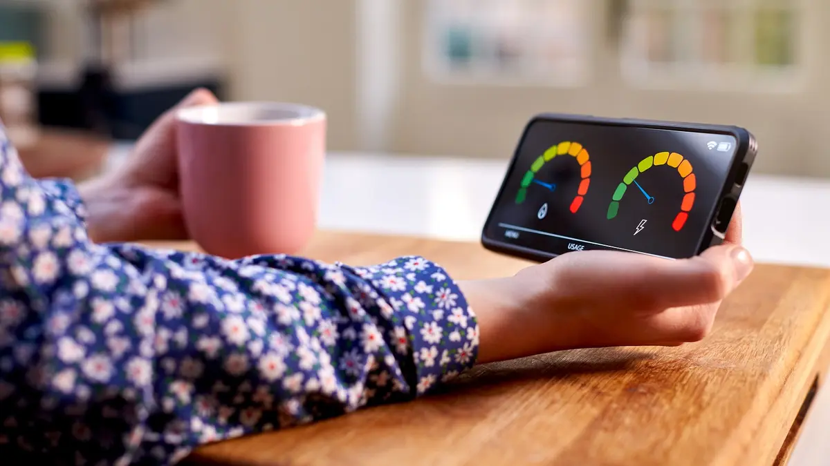 Eine Hand hält ein Smartphone, auf dem Anzeigen für Strom- und Wärmeverbrauch zu sehen sind.