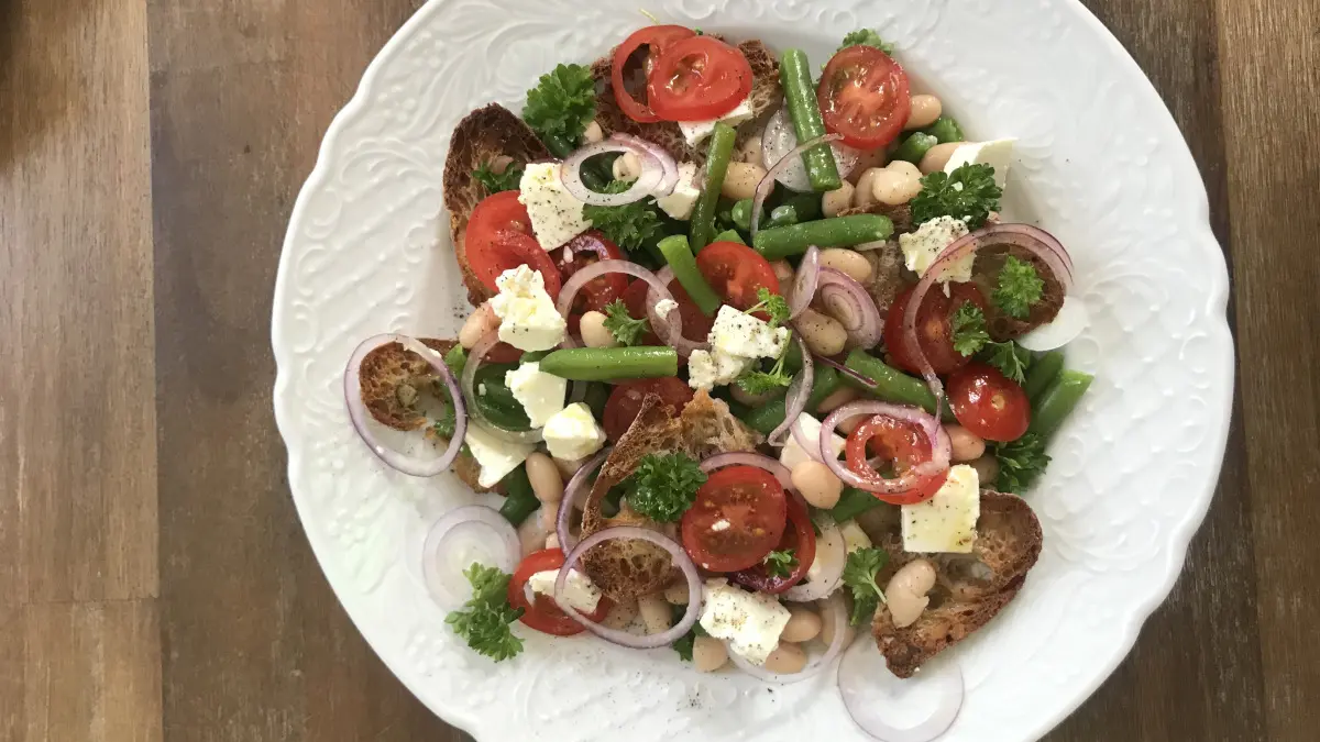 Ein Teller mit Brotsalat mit grünen und weißen Bohnen