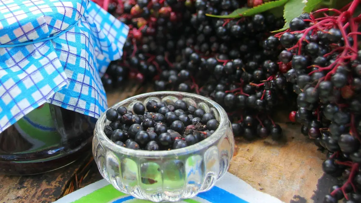 Eine Schüssel mit Holunderbeeren und ein Glas mit Holundermarmelade