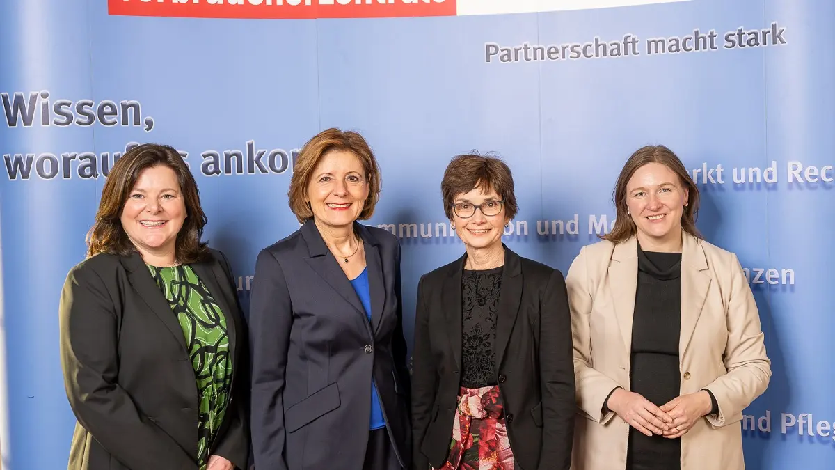 Vier Frauen stehen vor einer blauen Wand und blicken in die Kamera.