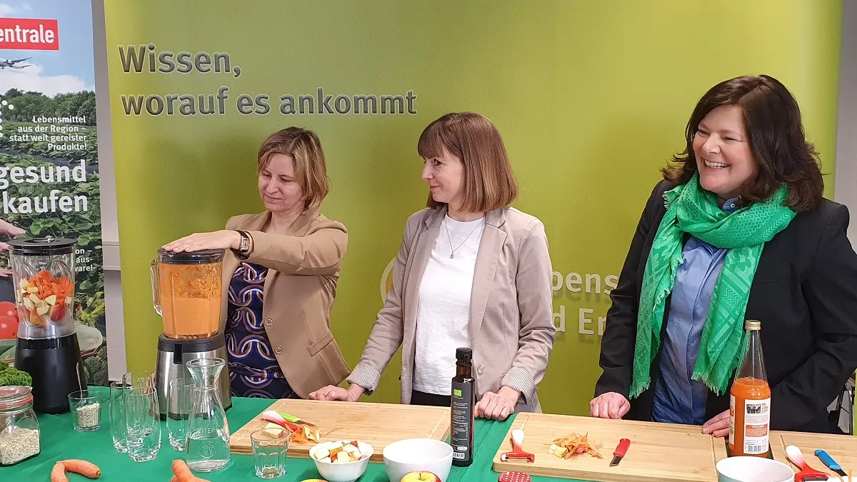 Drei Frauen mixen einen Smoothie.