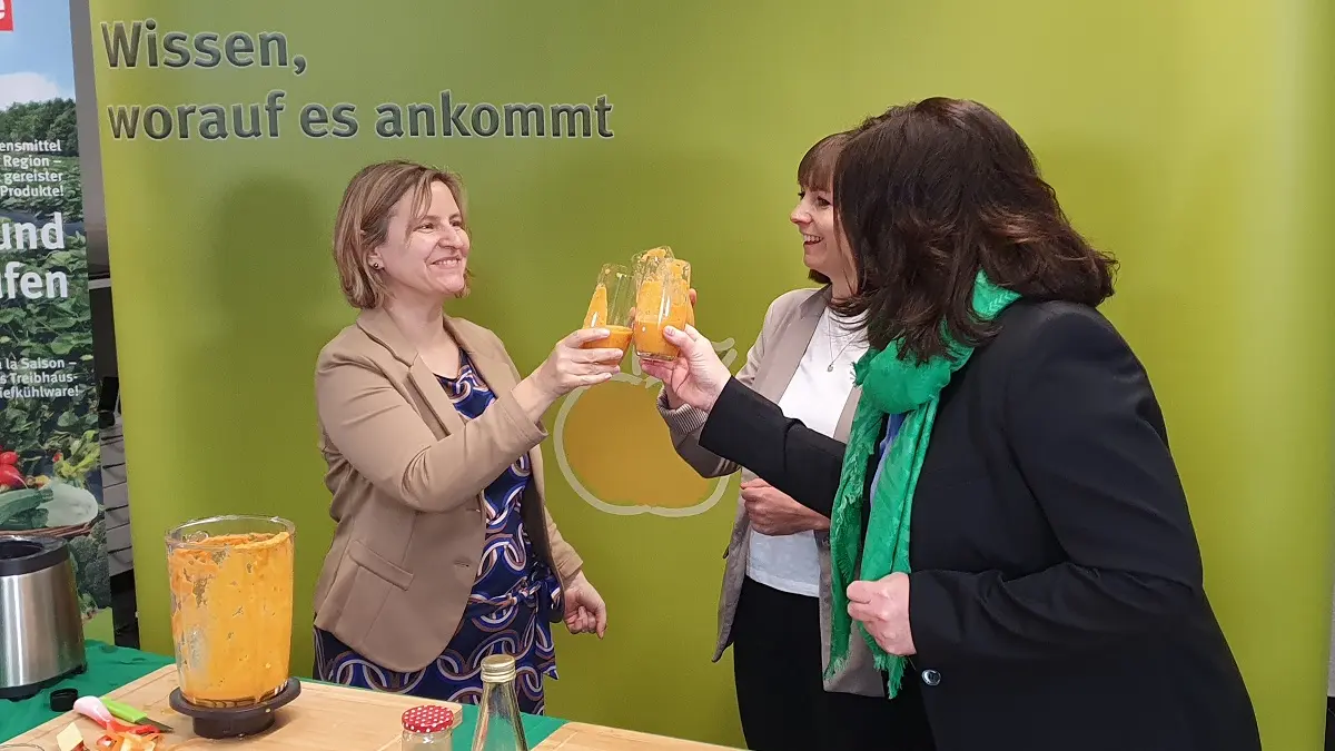 Drei Frauen stoßen mit einem Gemüsesmoothie an.