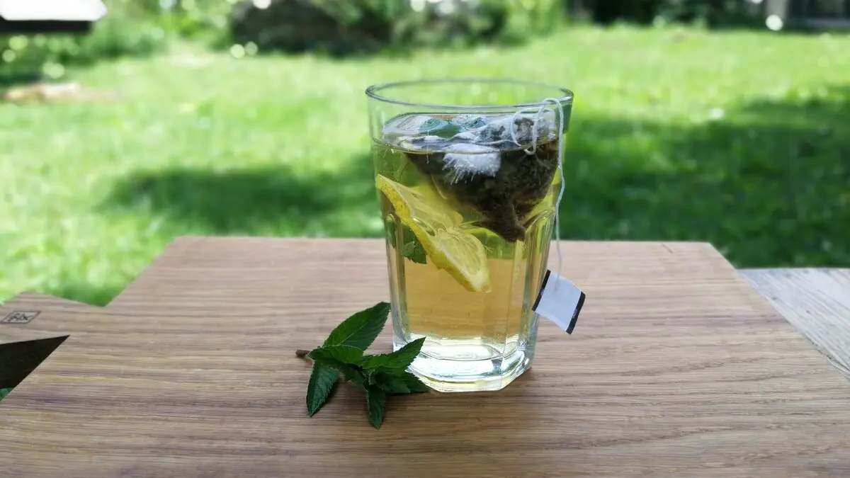 Ein Glas mit Cold Brew Tee steht auf einem Tisch im Garten.