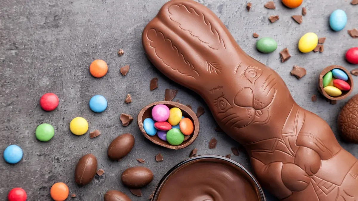 Ein Schokoladenosterhase umgeben von Schokoladeneiern und Schokoladenlinsen.