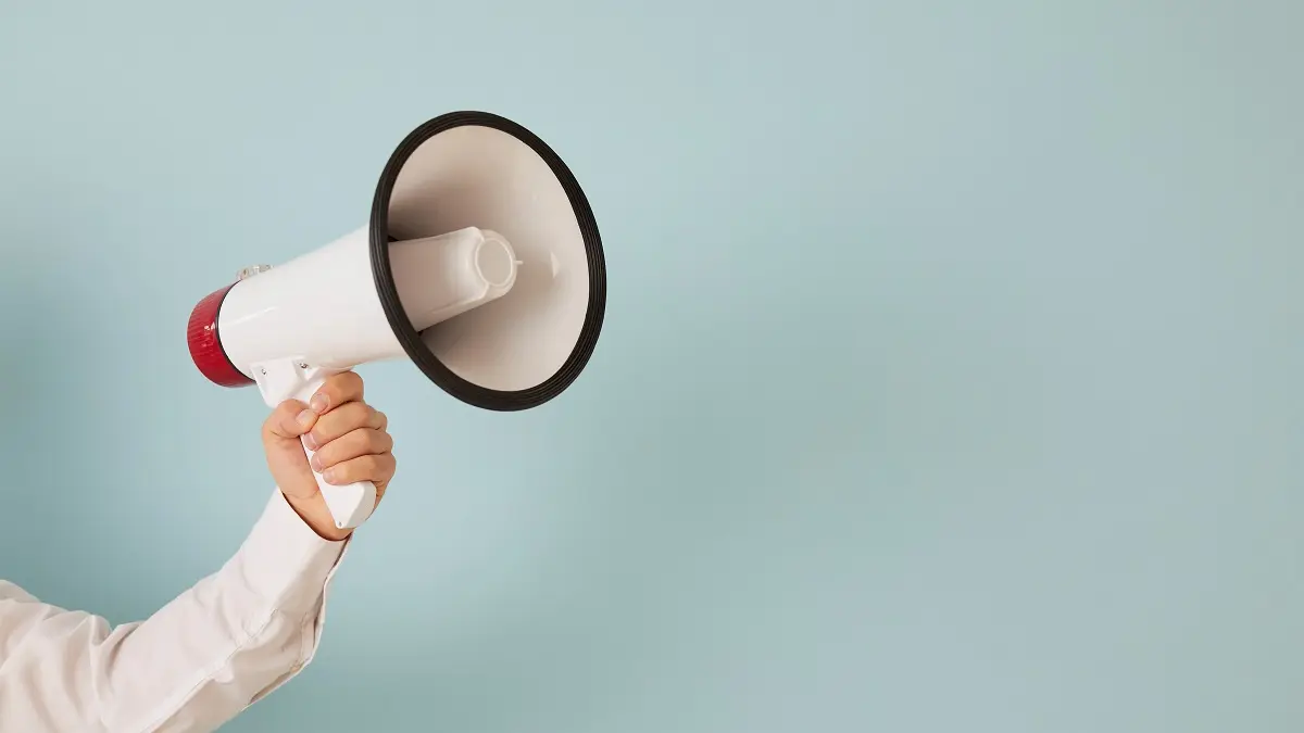 Ein Arm hält ein Megaphone ins Bild.