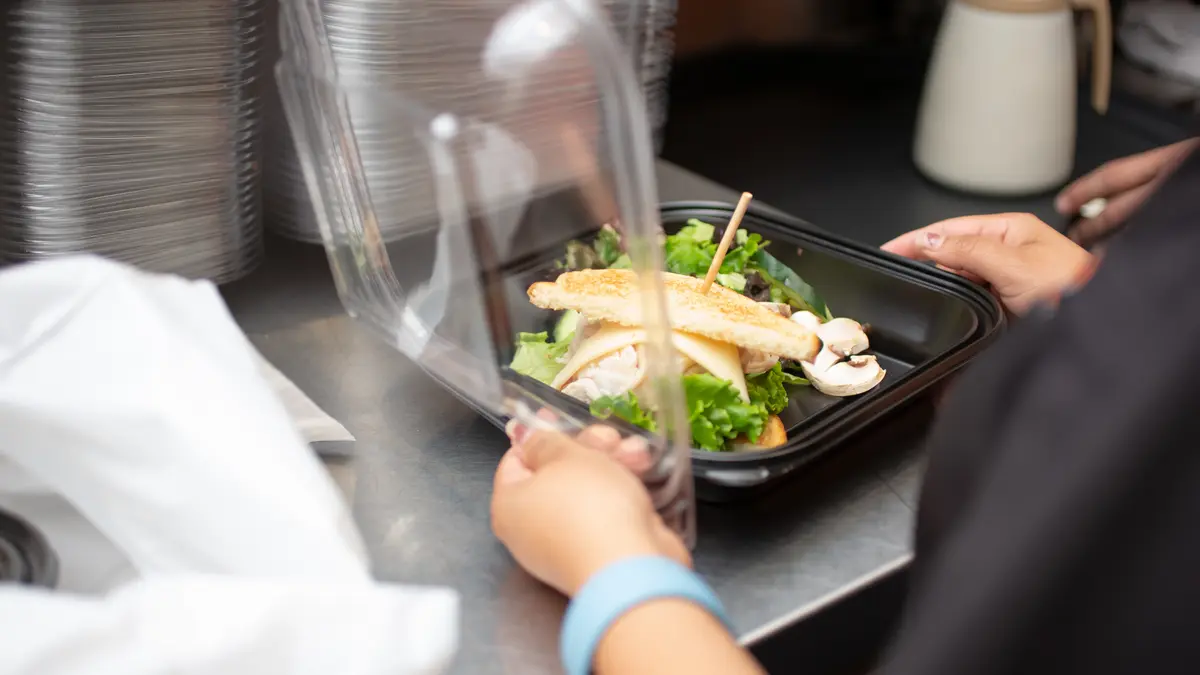 Frau verpackt Essen für einen Lieferdienst in einem Einwegbehälter