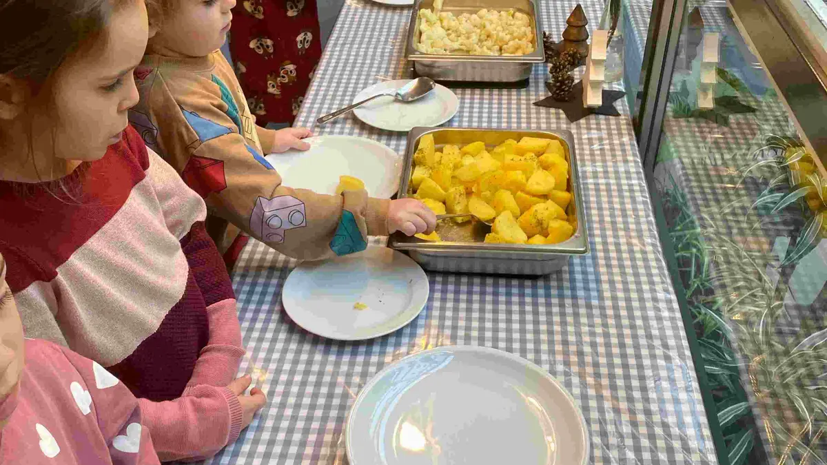 Kinder stehen am Mittagessens-Büffet und wählen aus.