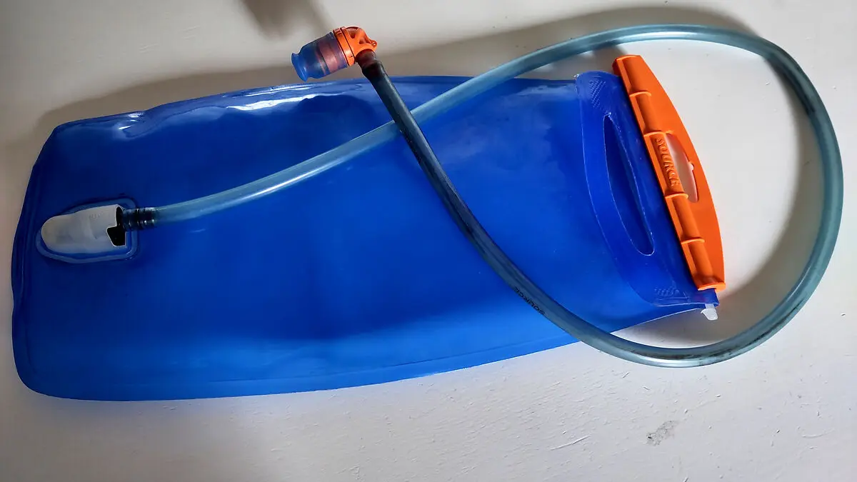 Eine blaue Trinkblase mit Schlauch liegt auf einem Tisch.