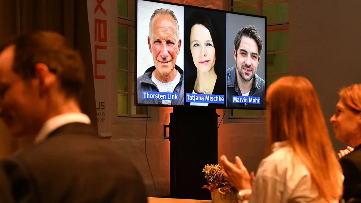 Teilnehmende auf einem Videoscreen