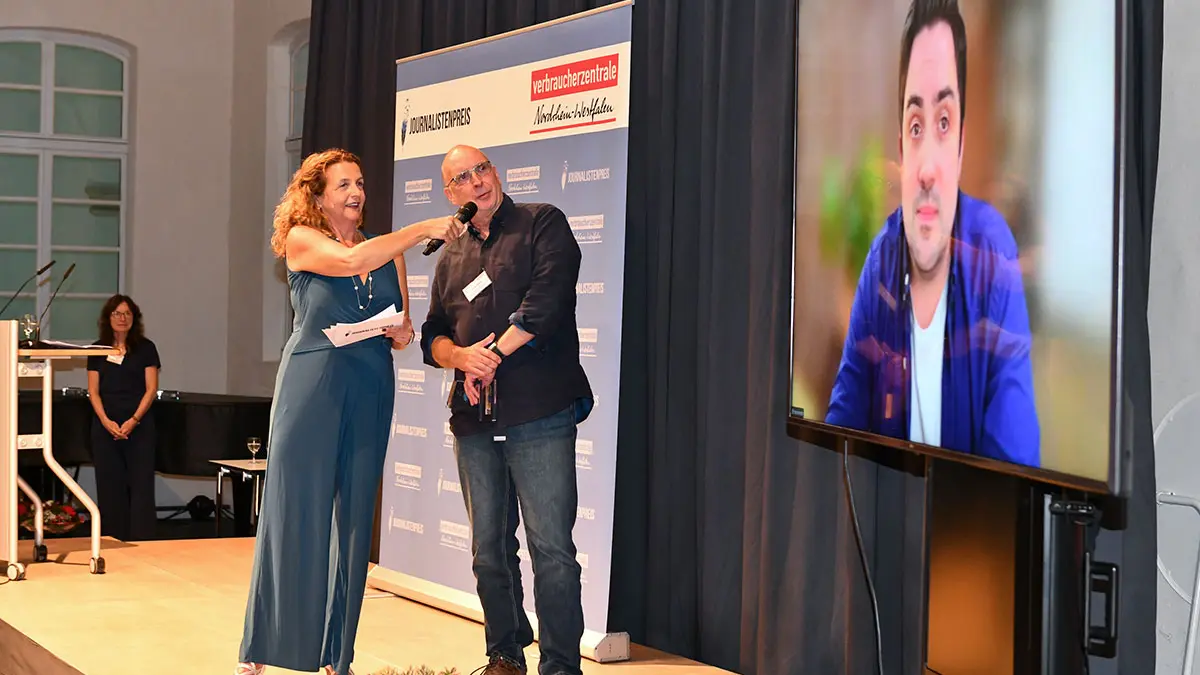 Moderatorin und Jurymitglied und zugeschaltetem Gewinner auf Videoscreen