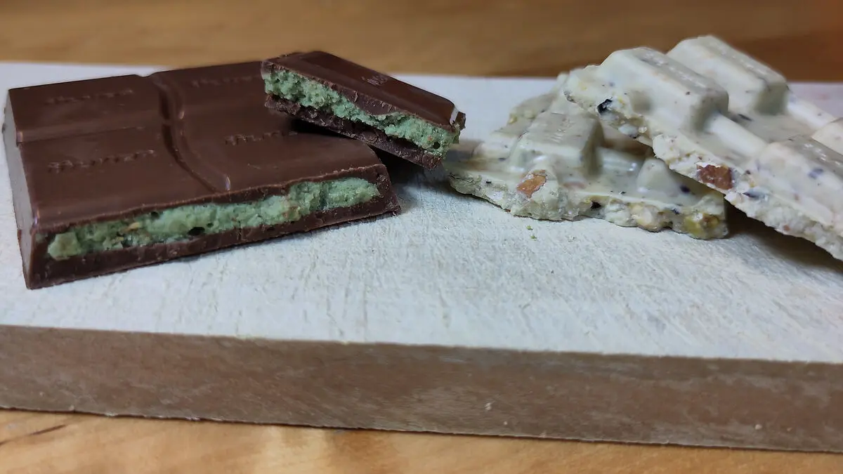 Stücke von Vollmilch- und weißer Dubaischokolade auf einem Schneidebrett