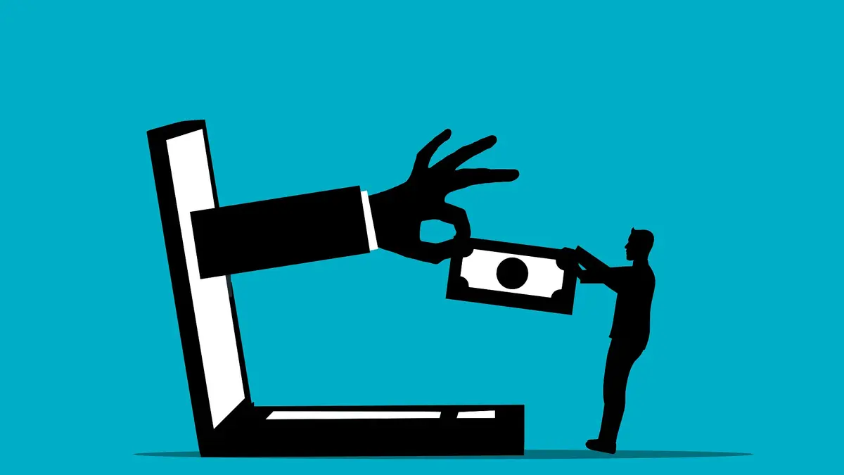 Hand zieht Geld in den Laptop