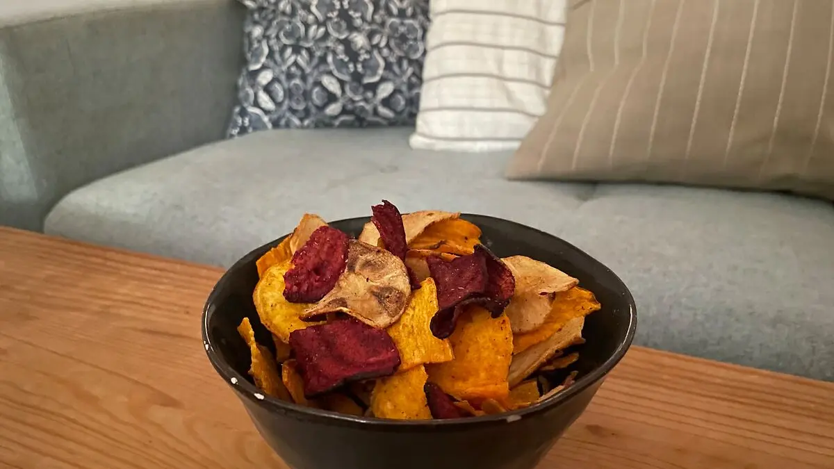 Eine Schüssel mit Gemüsechips steht auf einem Couchtisch.