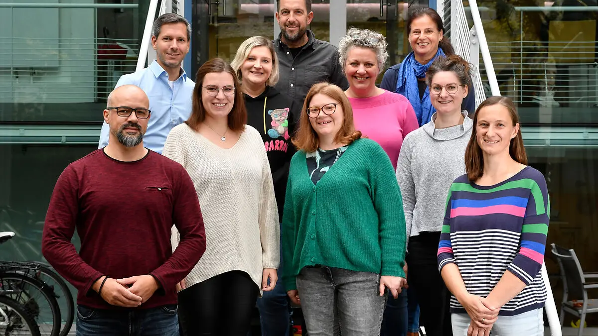 Das Team aus 10 Personen des Projekts VLJM steht auf einer Treppe und bilckt in die Kamera.