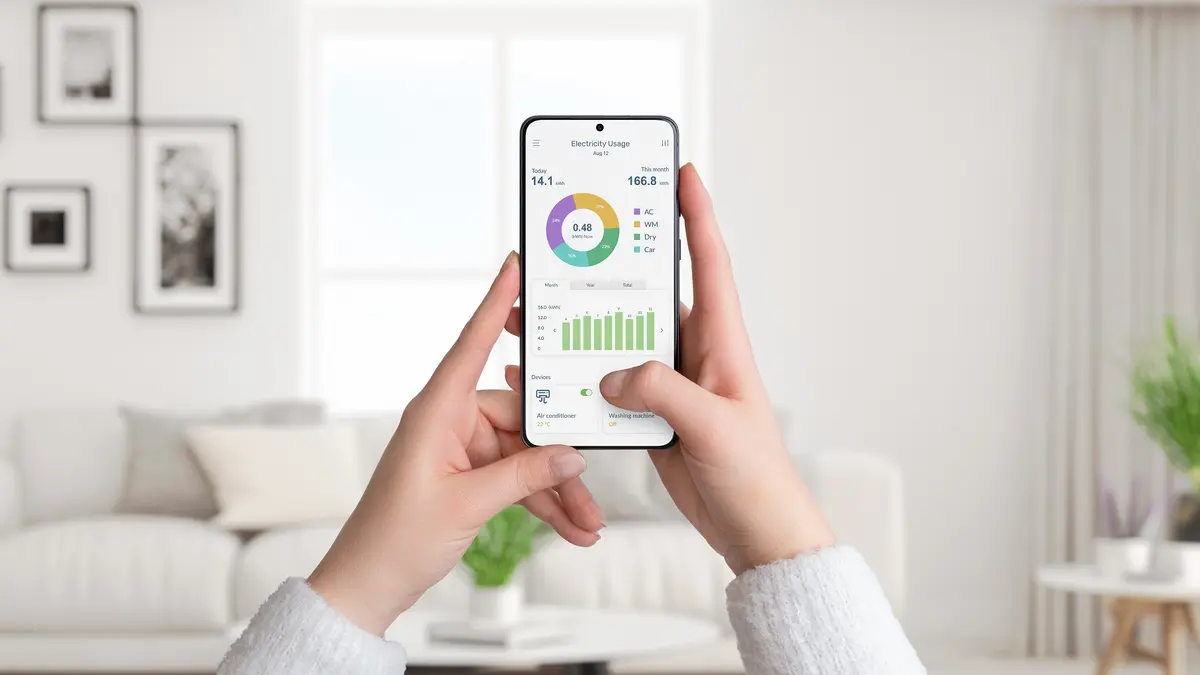 Eine Frau hält ein Smartphone mit einer Stromverbrauch-App.