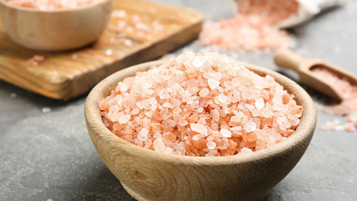 Eine Holzschüssel mit rotem Hawaii-Salz steht auf einer schwarzen Arbeitsfläche.